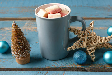 Wall Mural - Cup of hot chocolate with marshmallows and Christmas decorations on blue wooden background