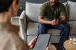 © Seventyfour - Cropped shot of African American army veteran talking to female psychologist in therapy session copy space