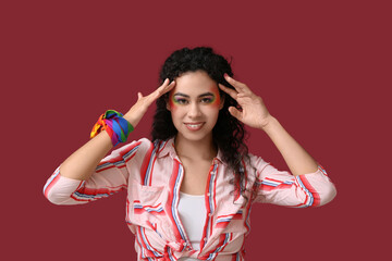 Poster - Young African-American woman with rainbow handkerchief on red background. LGBT concept