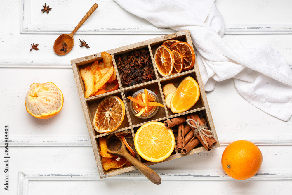 Wooden box with aromatic spices and fresh orange on light background