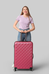 Sticker - Beautiful young woman with suitcase on grey background