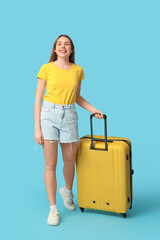 Sticker - Beautiful young woman with yellow suitcase on blue background