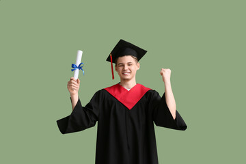 Happy male graduate with diploma on green background