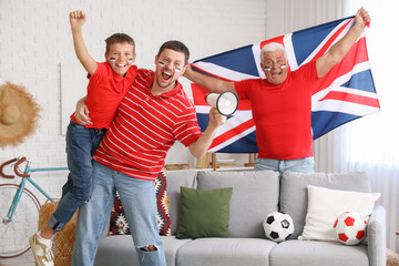 Wall Mural - Man with his father and son cheering for football team with megaphone, soccer balls and Great Britain flag in living room