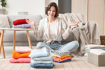 Young woman folding different clothes on floor at home