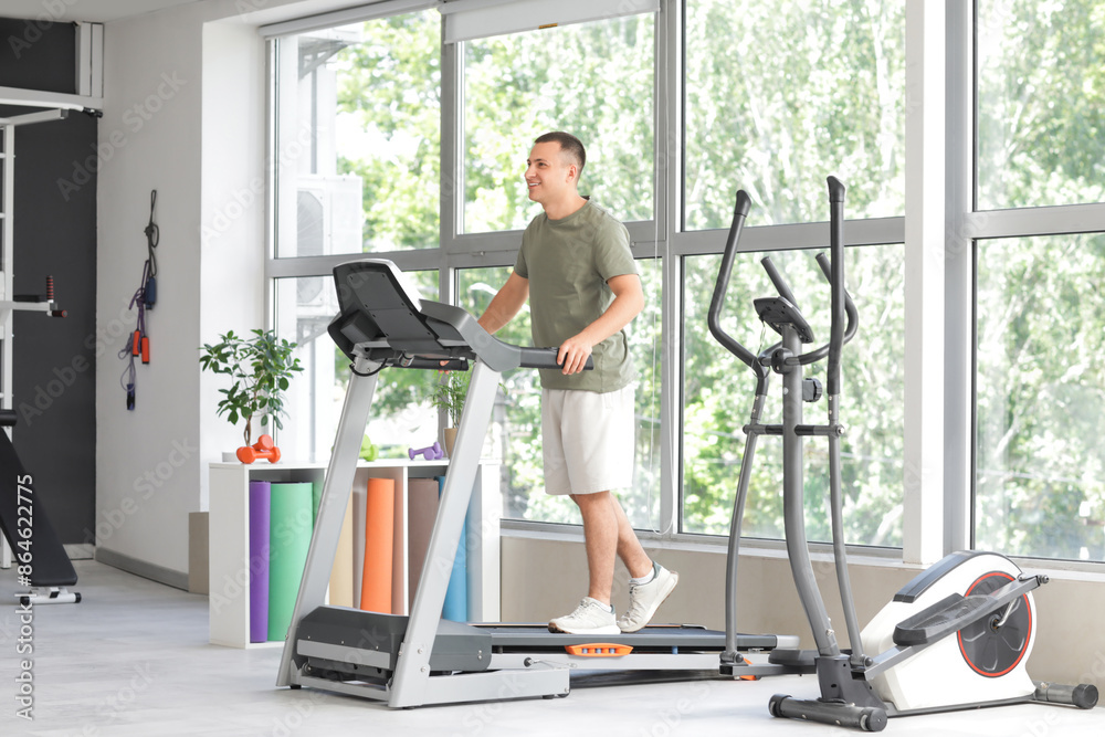 Sporty young man training on treadmill in gym