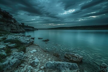Wall Mural - A rocky shoreline with a body of water in the background. The water is calm and the sky is dark and cloudy