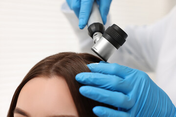 Canvas Print - Trichologist with dermatoscope examining patient`s hair in clinic, closeup