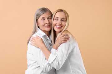 Wall Mural - Family portrait of young woman and her mother on beige background