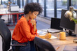 © Wavebreak Media - African American businesswoman writing notes at desk with laptop in modern office