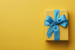 © Imane - yellow gift box with blue ribbon on yellow background perfect for special occasions