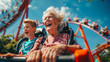 © chekart - An old gray-haired woman and a little boy ride a roller coaster. Grandma and grandson have fun at the amusement park. The scene is joyful and funny