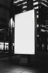 Wall Mural - A large white billboard is lit up at night in front of a building. The billboard is empty, with no text or images on it. Scene is one of emptiness and solitude