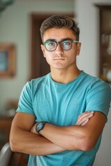 Poster - A young man wearing a blue shirt and glasses is standing with his arms crossed. He is looking at the camera with a serious expression on his face