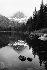 Wall Mural - A black and white photo of a lake with a mountain in the background. The water is calm and the reflection of the mountain can be seen in the water