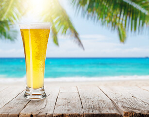 Poster - Glass of beer on a table with a stunning sea and beach background