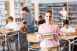© JackF - Young girl standing in reading room of library with pile of books in hands.