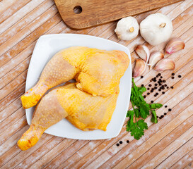 Wall Mural - Raw poultry, fresh chicken legs quarters with condiments on wooden table