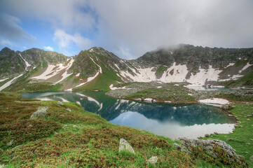 Wall Mural - Lake with clear water in a mountain valley. Mountains are reflected in the water.