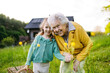 © Halfpoint - Granddaughter spending time with elderly grandma, picking wildflowers. Senior lady spending time in nature.