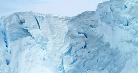 Wall Mural - Arctic glacier close up aerial view. Snow covered blue ice wall iceberg in Antarctica, snowy frozen structure. Drone panorama. Natural background, winter wallpaper. Climate change and global warming