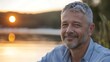 © Sourav Mittal - Close up portrait of a happy smiling middle aged man with grey hair and a short beard sitting by the lake at sunset, concept copy for health care or beauty treatment advertising, real photo taken usin