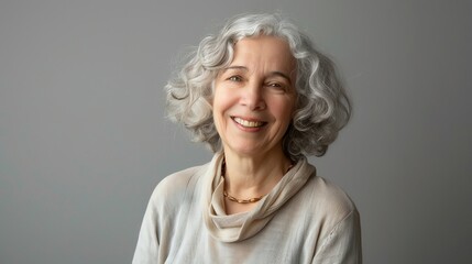 A woman with gray curly hair and a white sweater smiles at the camera.
