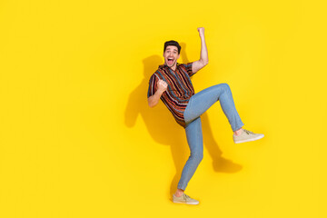 Wall Mural - Full size photo of nice young man raise fists empty space wear shirt isolated on yellow color background