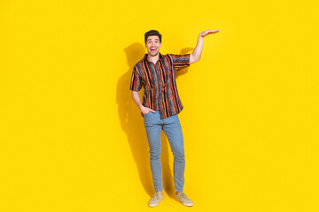 Wall Mural - Full size photo of nice young man measure empty space wear shirt isolated on yellow color background
