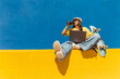 © VISTA by Westend61 - Woman with laptop drinking water and sitting on wall