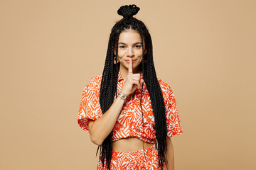 Wall Mural - Young fun Latin woman she wears orange casual clothes say hush be quiet with finger on lips shhh gesture look camera isolated on plain pastel light beige background studio portrait. Lifestyle concept.