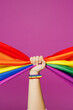 © ViDi Studio - Close up cropped female hold in hand striped rainbow colorful flag isolated on pastel plain purple color wall background studio. Pride day June month love LGBTQ concept Copy space advertising mock up
