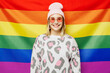 © ViDi Studio - Young happy smiling satisfied cheerful lesbian woman she wear pink animal clothes hat sunglasses look camera stand on rainbow flag background studio portrait. Pride day June month love LGBTQ concept.