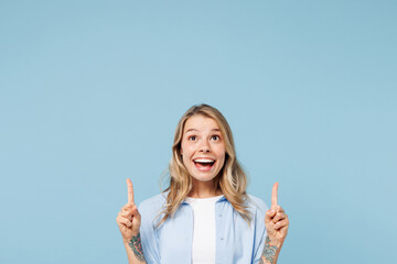 Wall Mural - Young smiling happy woman she wearing white top shirt casual clothes point index finger overhead on area mockup isolated on plain pastel light blue cyan background studio portrait. Lifestyle concept.