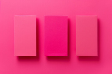 Poster - A flat lay of three pink paper sheets arranged at an angle, creating geometric shapes on the solid color background. The sheets have sharp edges and a glossy finish, adding to their elegance. 