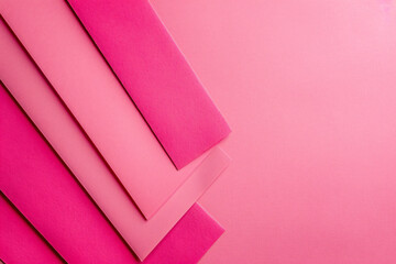 Poster - A flat lay of three pink paper sheets arranged at an angle, creating geometric shapes on the solid color background. The sheets have sharp edges and a glossy finish, adding to their elegance. 