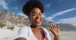 © peopleimages.com - Outdoor, portrait and hand of black woman in video call, visual communication and greeting in beach. Female person, influencer and waving in social media, vlogging and hello on vacation in California