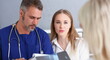 © H_Ko - Smiling handsome doctor communicate with patient holding silver pen and showing pad. Physical agreement signature disease prevention interpreter translator prescribe remedy healthy lifestyle