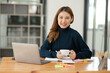 © Thitisak - ฺAsia Businesswoman sitting and working using laptop to chat with customers online in office