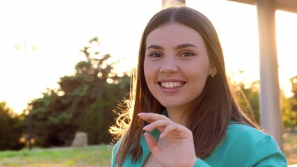 Poster - This video features a young woman standing outdoors in the evening. The sun is setting, casting a warm, golden light on her face.