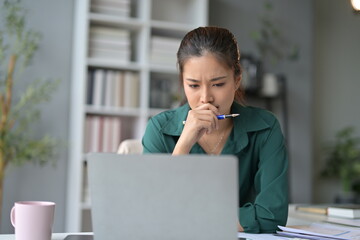 Poster - Stressed businesswoman biting pen, staring at laptop in home office, feeling pressure of work