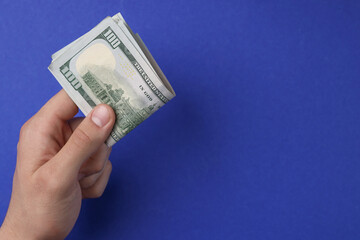 Wall Mural - Money exchange. Man holding dollar banknotes on blue background, top view. Space for text