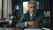 © Chatchanan - A senior executive seated at a desk, with hands folded and looking directly into the camera, exuding authority and experience