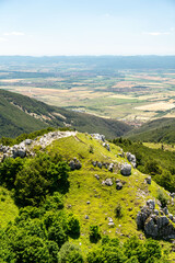 Hiker standing on top of mountain with valley view on sunny summer day