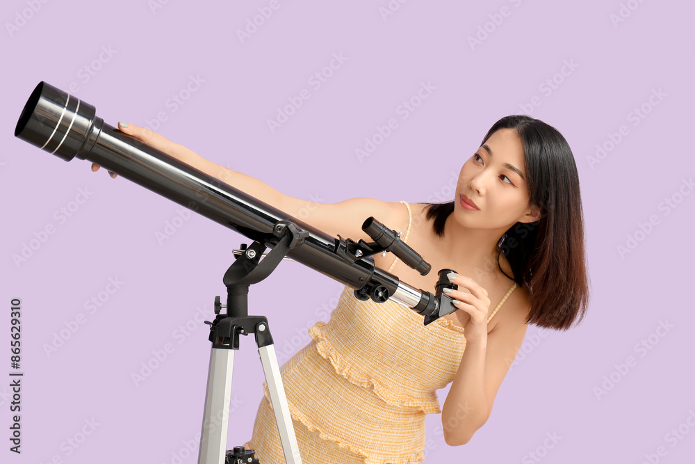 Young Asian woman using telescope on lilac background