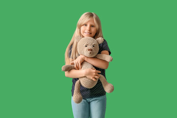 Poster - Cute little girl with plush teddy bear on green background