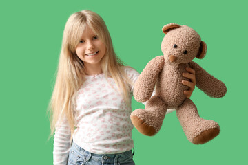 Wall Mural - Cute little girl with plush teddy bear on green background