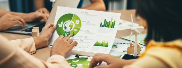 Wall Mural - Professional businessman interested in invested in green businesses when he see rising graph on table with environmental document and wooden block scatter around. Closeup. Focus on hand. Delineation.