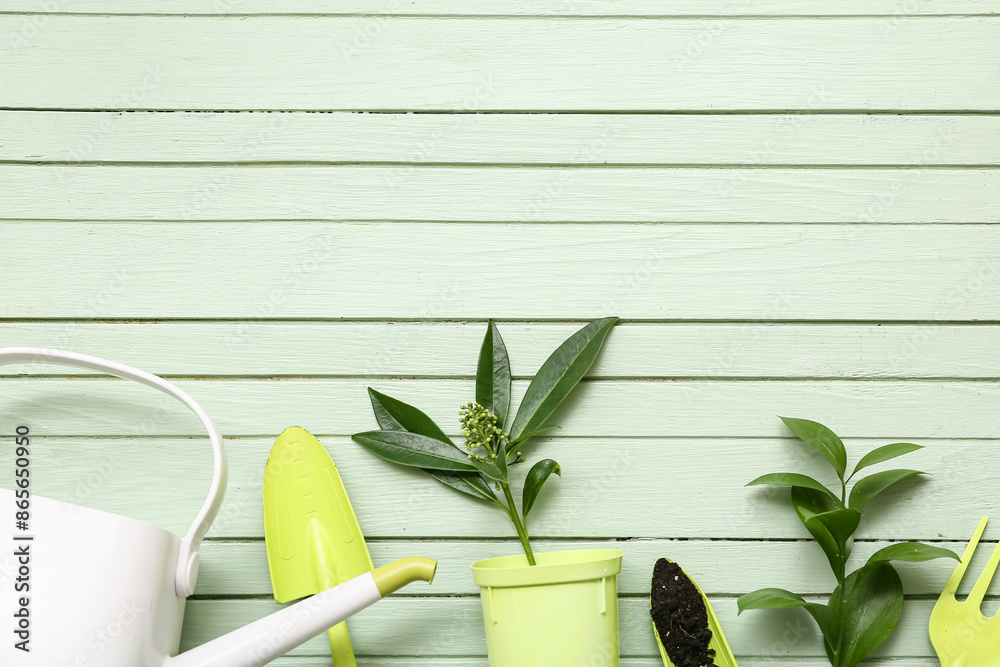 Gardening tools with plants and soil on green wooden background. Top view