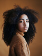 © KC Radler - Portrait of a Young Woman with Curly Hair in a Brown Sweater Against a Warm Background